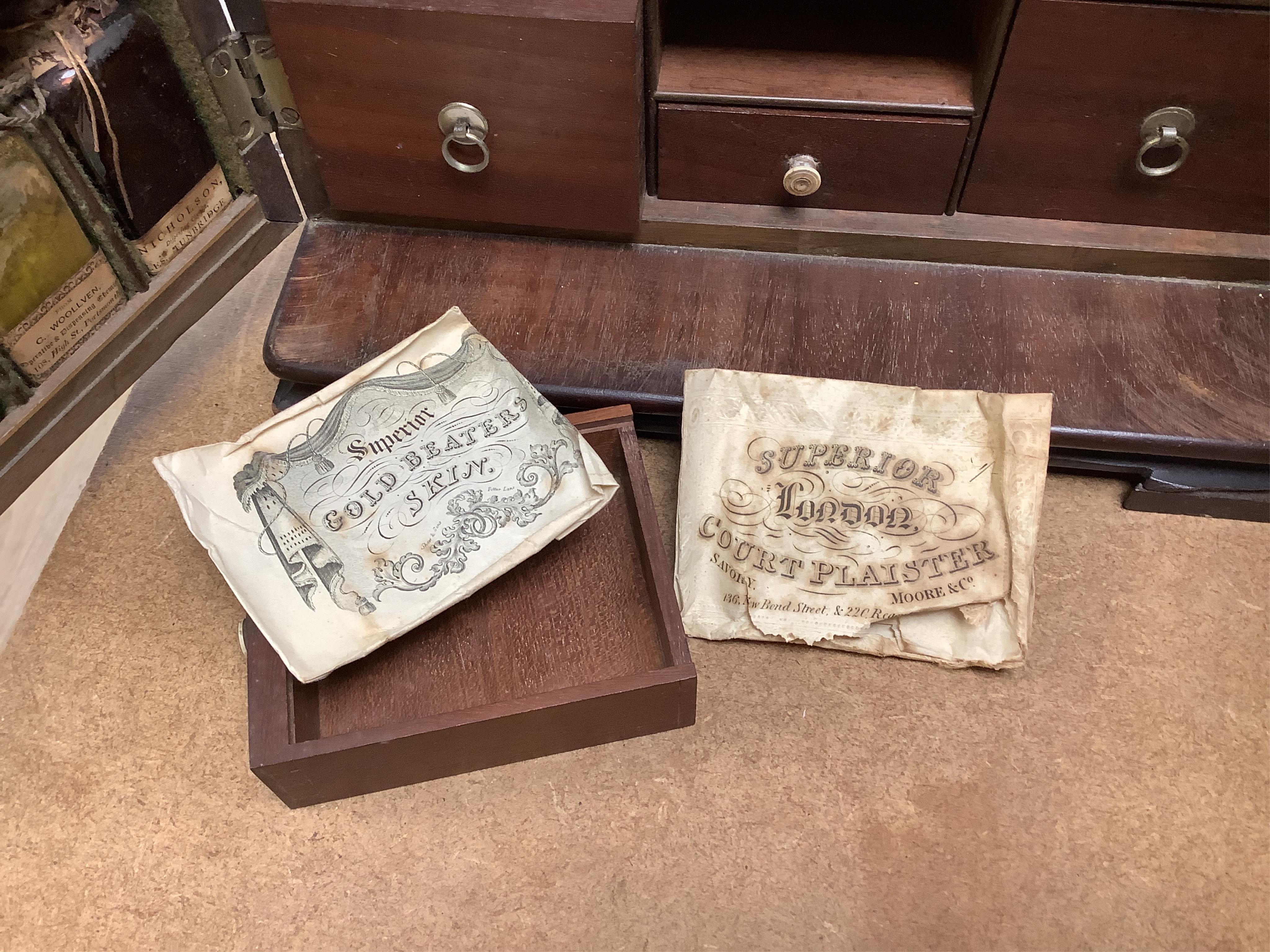 A 19th century mahogany apothecary cabinet, containing 20 bottles of various medicinal compounds and poisons, some sealed, all with paper labels, mainly for ‘C. Woollven, Operative & Dispensing Chemist, 108, High Street,